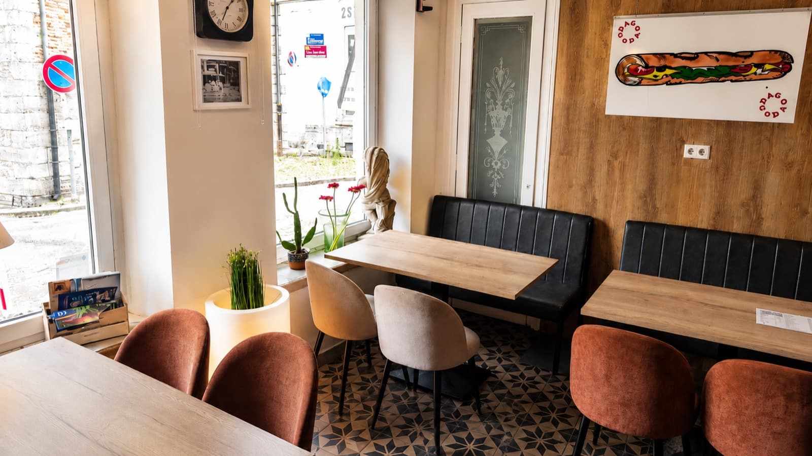 L’intérieur de DAGO-GODA : tables en bois, banquettes noires, fauteuils terracotta et fresque sandwich au mur